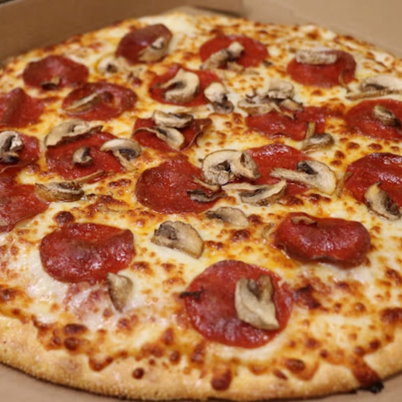 A close-up of a Watt A Pizza pepperoni and mushroom pizza in a cardboard box.