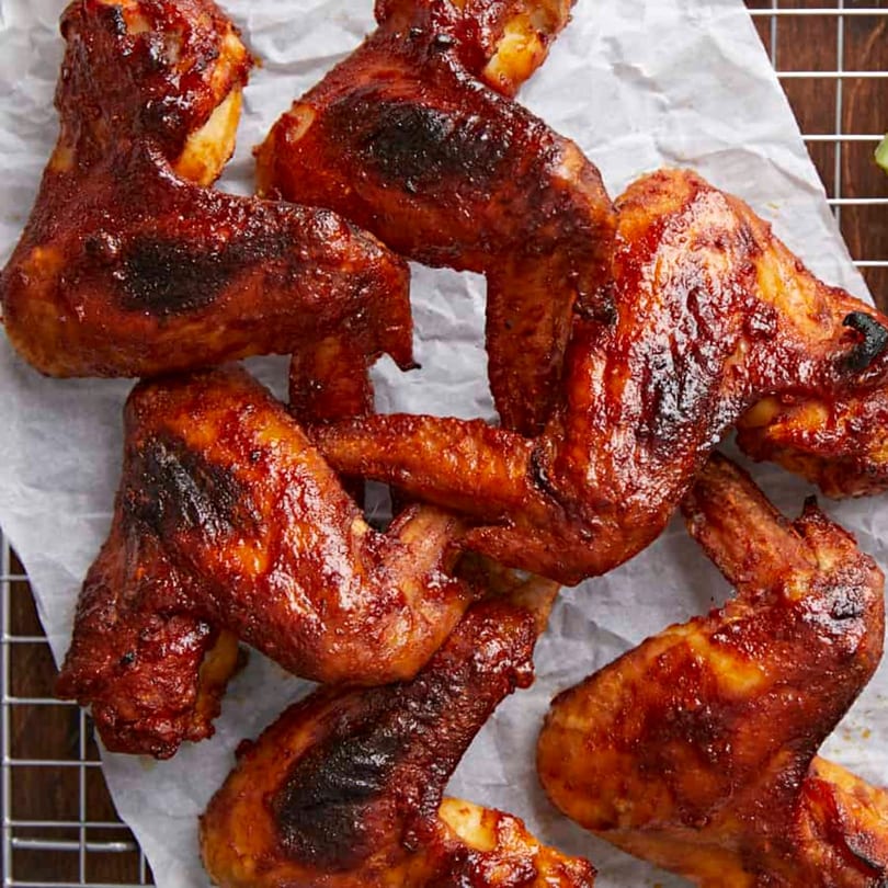 Watt A Pizza's crispy, saucy chicken wings with a rich, dark glaze on parchment paper.